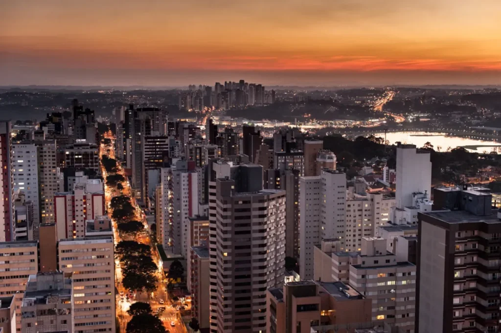 Bairro urbano em Curitiba com edifícios de diferentes épocas e pessoas diversas.
