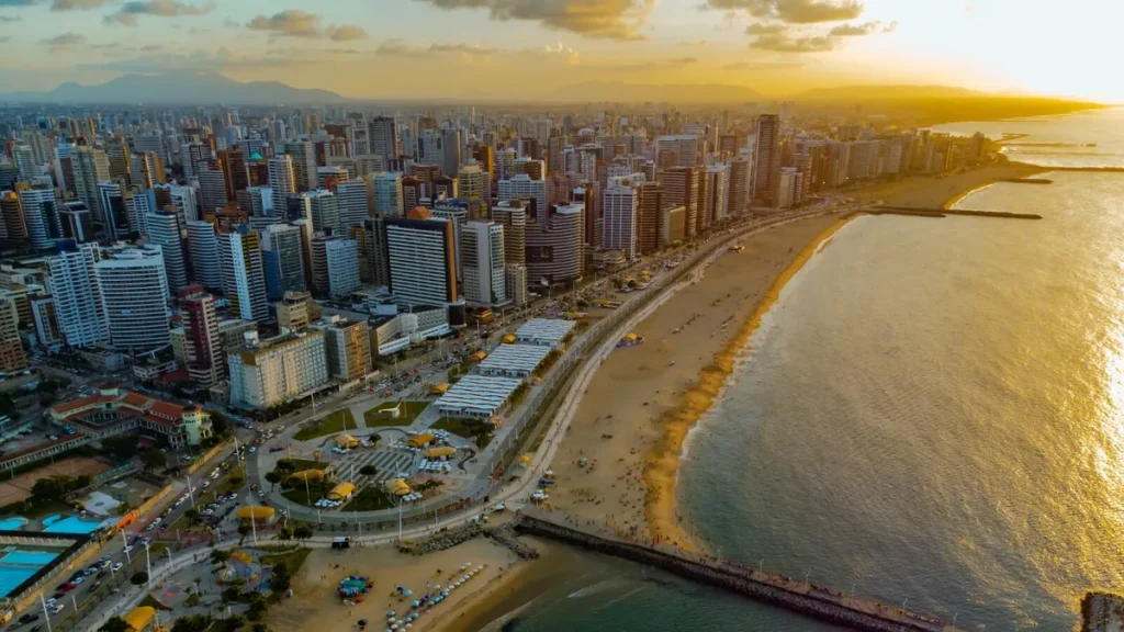 Rua movimentada em Fortaleza com prédios residenciais econômicos.