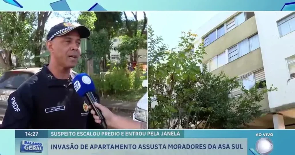Policial militar orienta moradores em frente a prédio residencial após invasão.