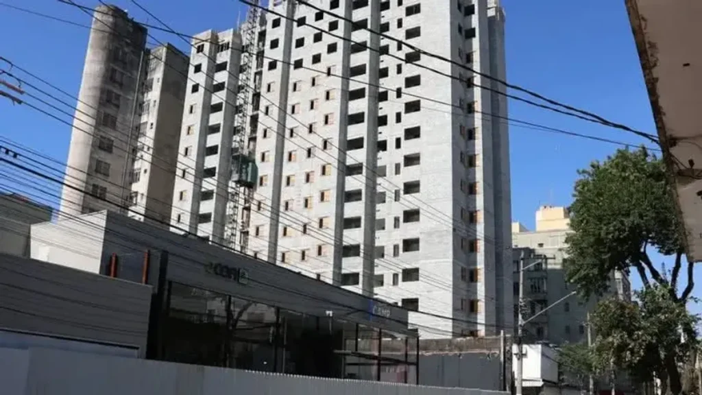 Conjunto habitacional popular em São Paulo com contraste de prédios modernos ao fundo.