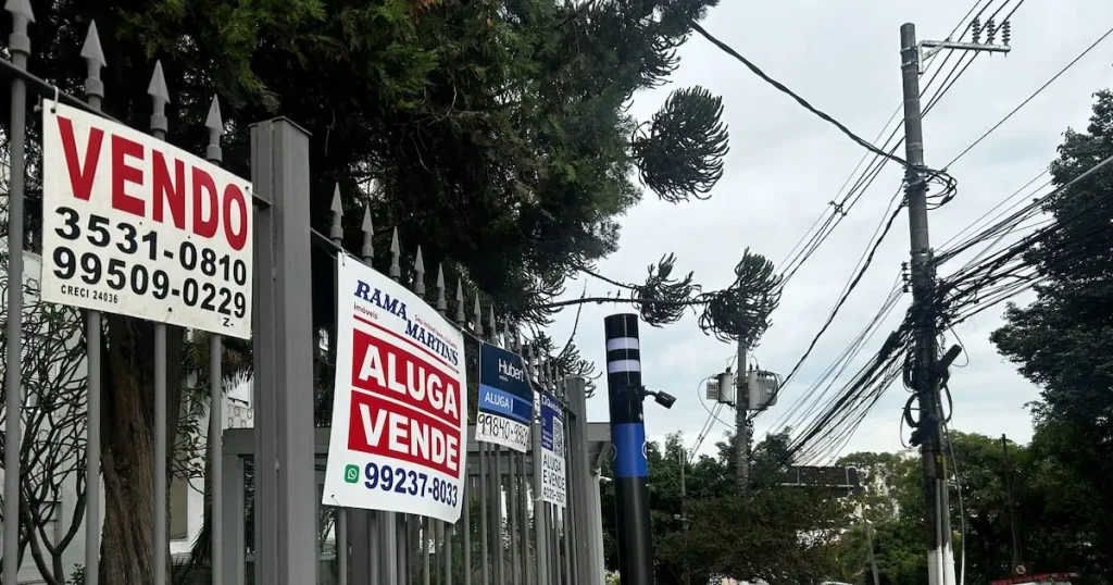 Família de classe média brasileira em frente a um apartamento alugado, com expressão pensativa sobre custos e o sonho da casa própria.