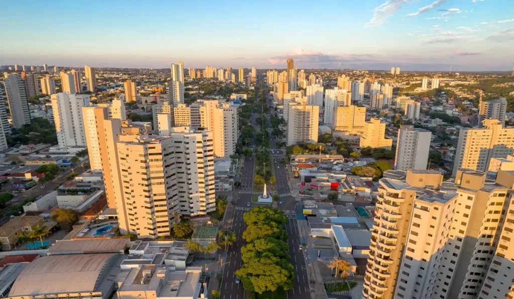 Edifício residencial moderno em Campo Grande com o pôr do sol ao fundo.