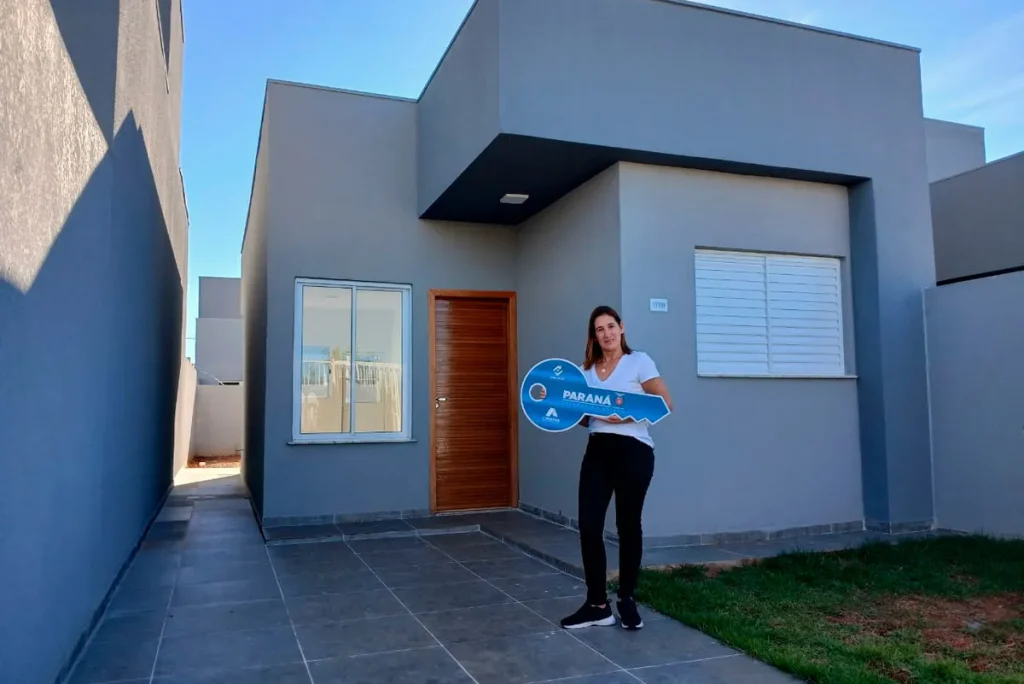 Mulher emocionada segurando chaves da casa própria subsidiada em Umuarama