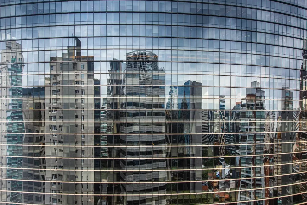 Edifício comercial moderno com fachada de vidro em centro urbano.