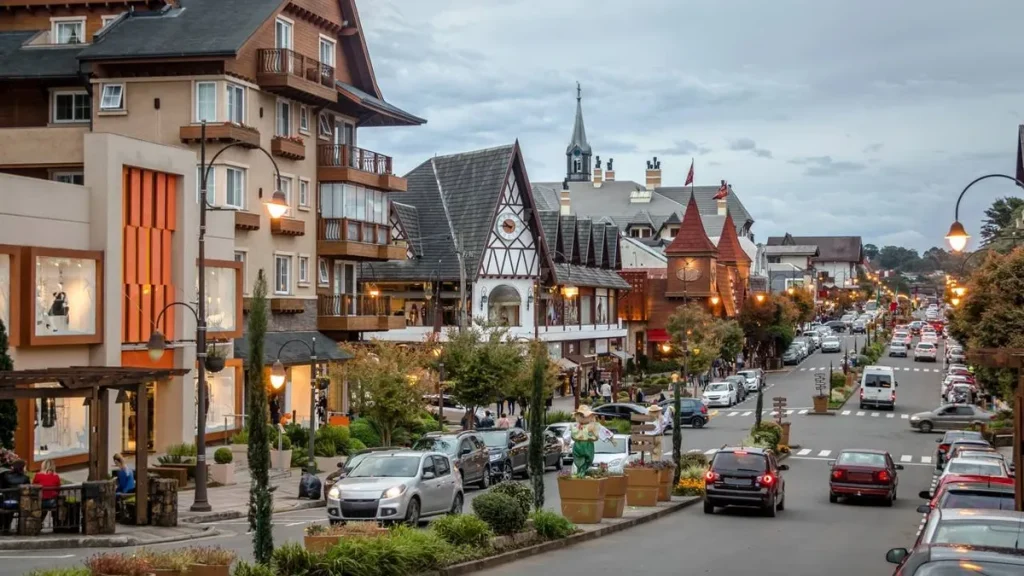 Rua principal em Gramado com arquitetura europeia, flores e pessoas caminhando.