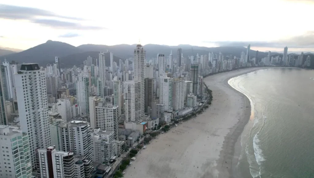 Skyline moderno de cidade litorânea em Santa Catarina com prédios de luxo ao pôr do sol