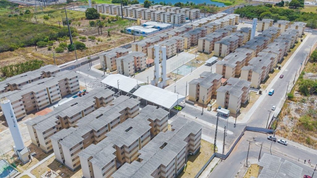 Construção de moradias populares do programa Minha Casa Minha Vida, com trabalhadores e maquinário em atividade.
