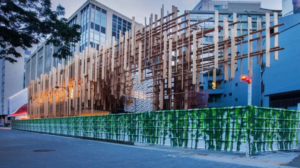 Edifício corporativo moderno com fachada de vidro e elementos de sustentabilidade, como painéis solares.