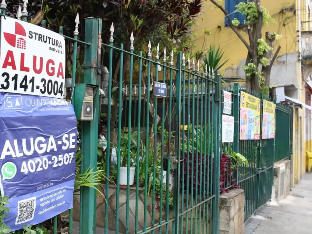 Fachada de pequeno comércio com placa de 'Aluga-se' e cadeado.