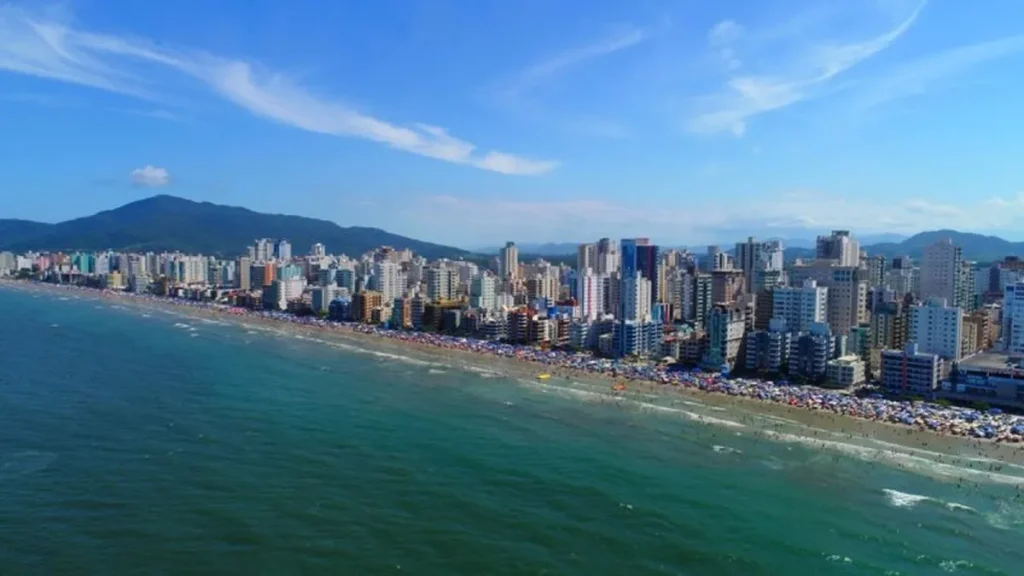 Vista aérea de Itapema, SC, destacando a praia e a arquitetura moderna dos edifícios residenciais.
